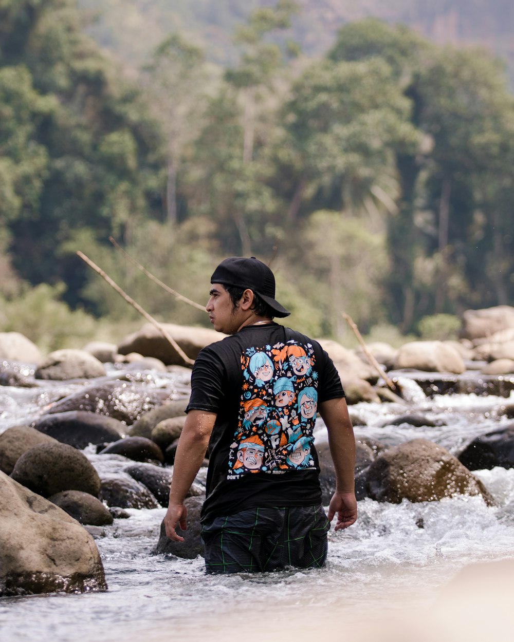 a man standing in a river next to a forest