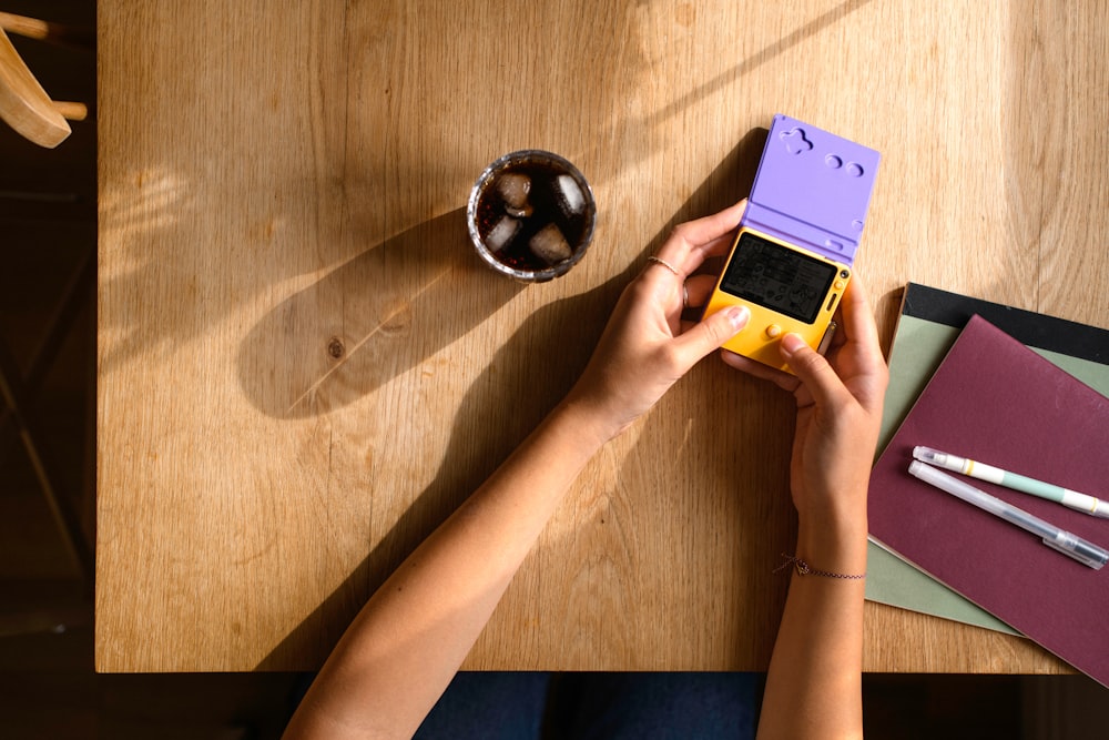 a person holding a cell phone on top of a wooden table