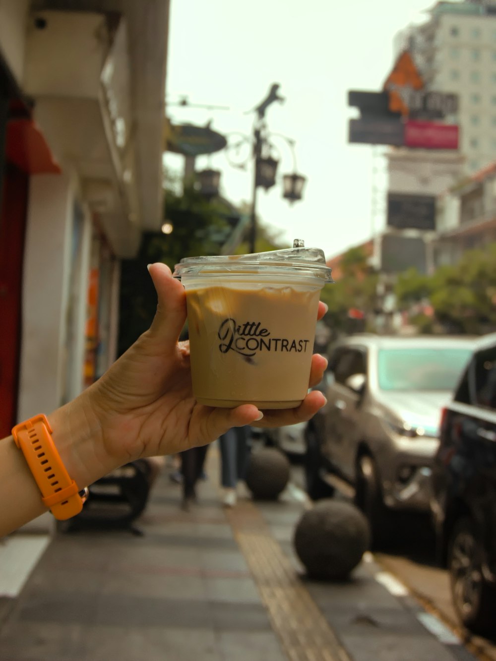 uma pessoa segurando uma xícara de café em uma rua da cidade