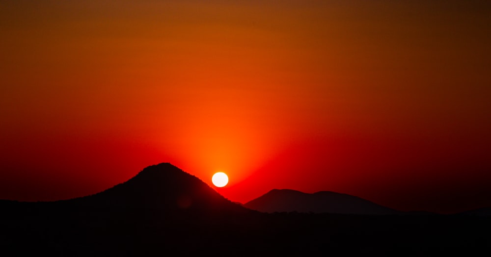 the sun is setting over a mountain range