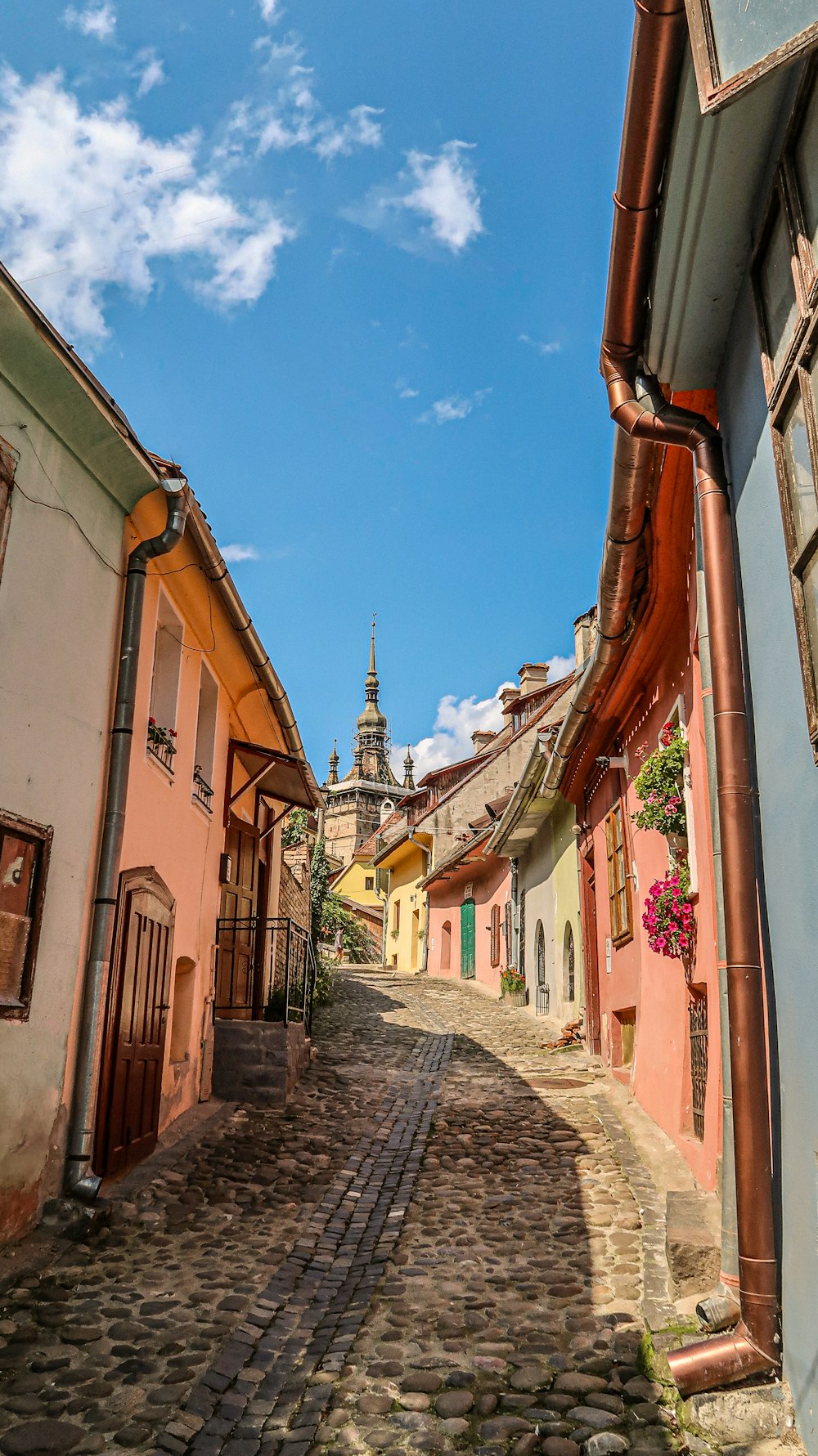 a cobblestone street with a clock tower in the background