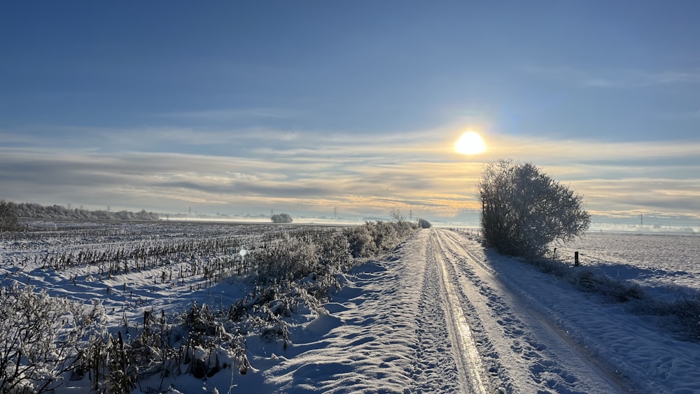 the sun is setting over a snowy road