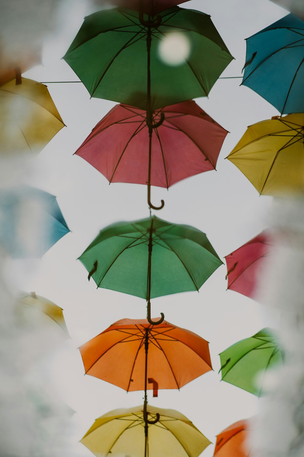 a group of multicolored umbrellas hanging from a ceiling