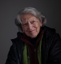 an older woman in a black jacket and green jacket