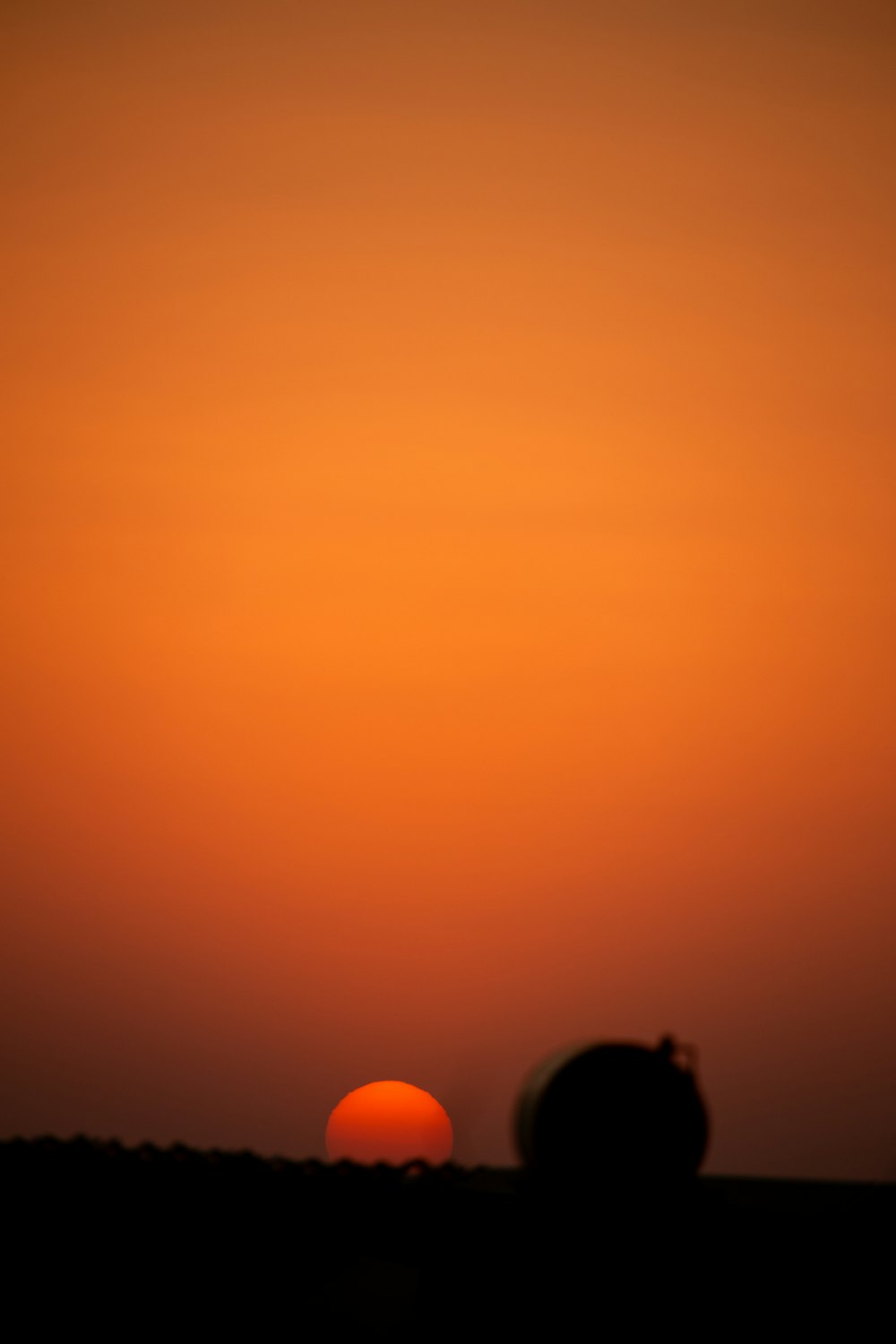 the sun is setting over a field of grass