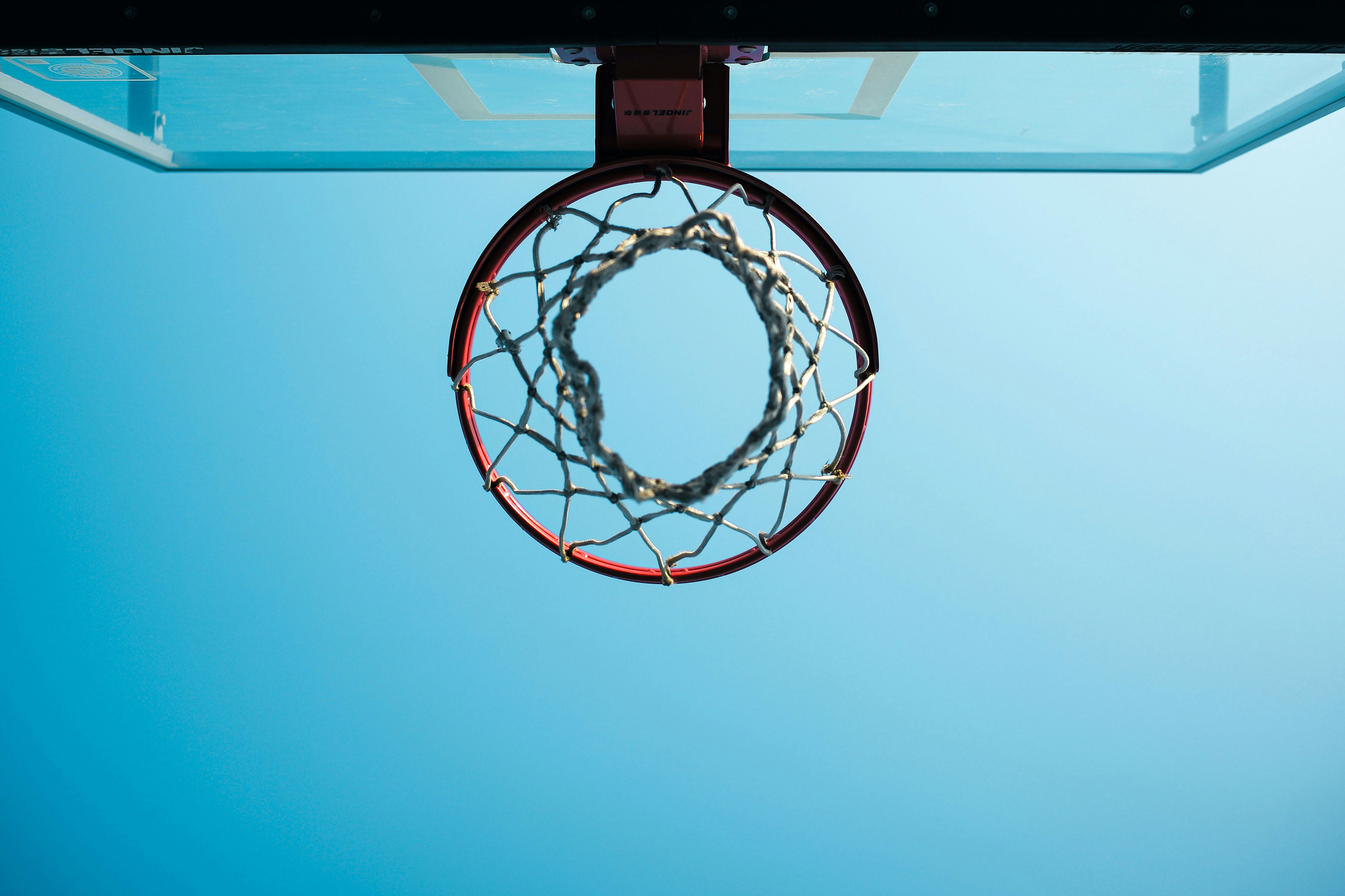 Upward View of a Basketball Hoop Against a Clear Blue Sky