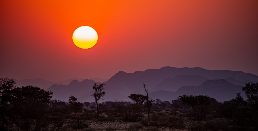 the sun is setting over the mountains in the desert