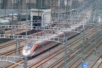 a silver train traveling down train tracks next to tall buildings