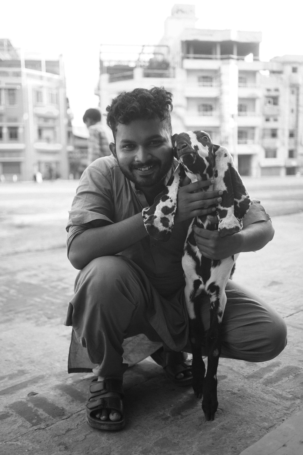 a man kneeling down holding a small dog