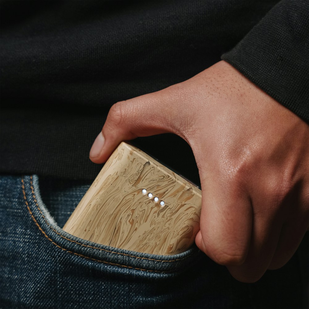 a person holding a wooden lighter in their pocket