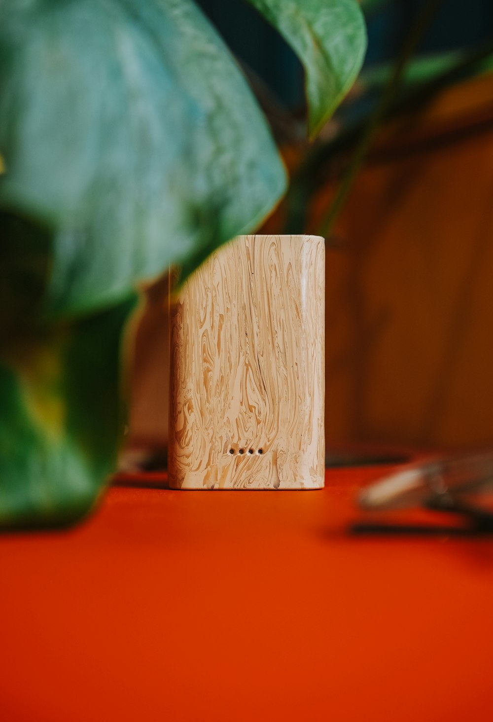 a wooden block sitting on top of a table next to a plant
