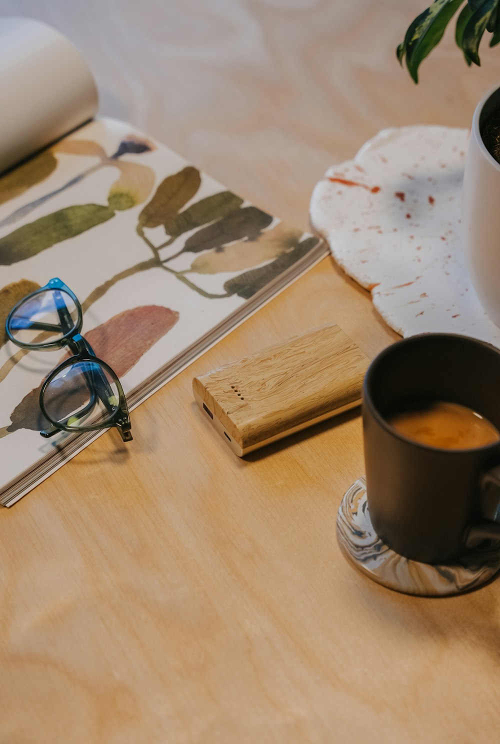 a wooden table topped with a cup of coffee and a notebook