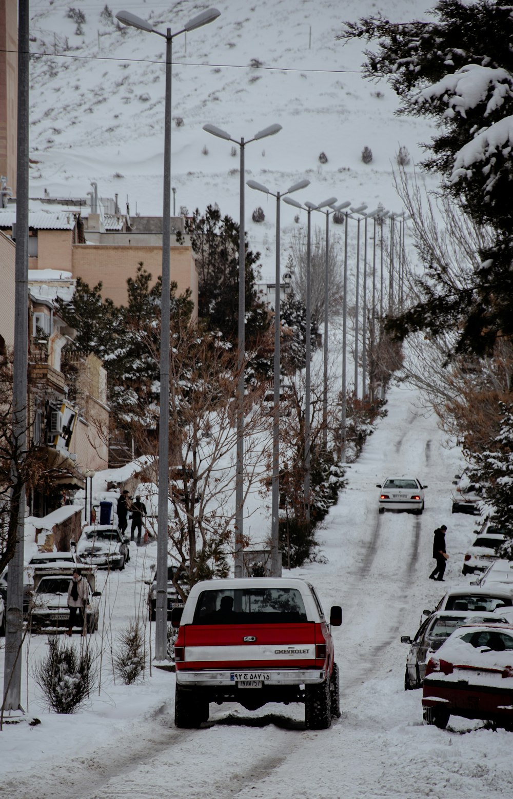 a red truck driving down a snow covered street