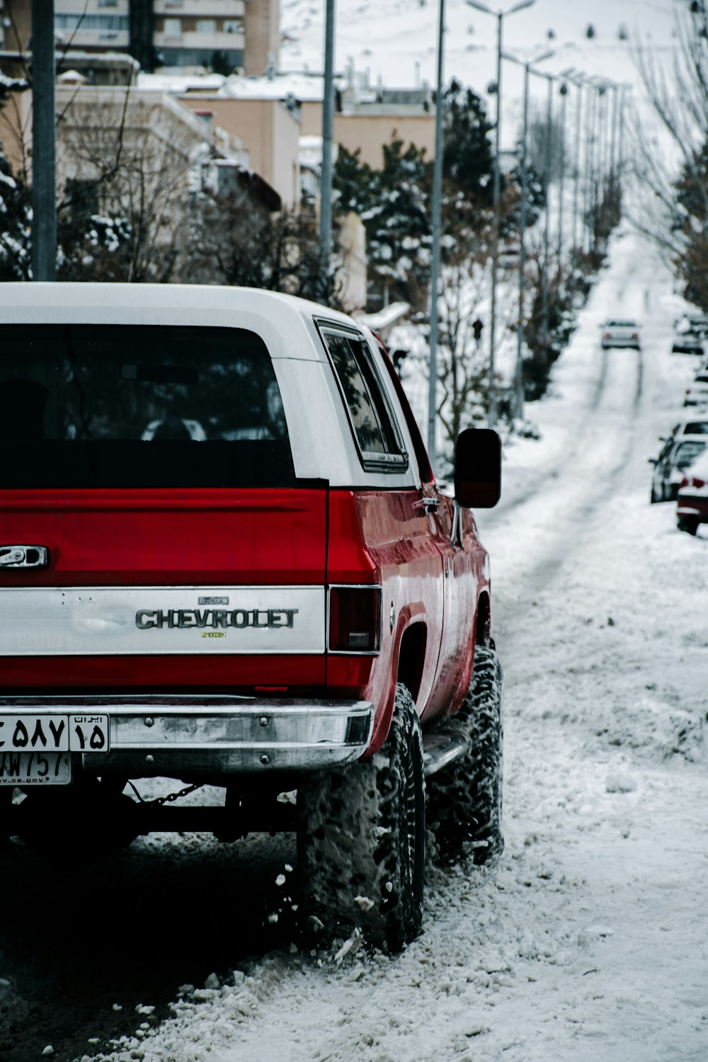 a red pick up truck parked on a snowy street
