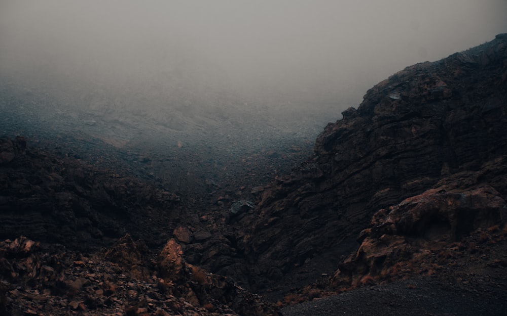 a foggy mountain landscape with rocks and grass