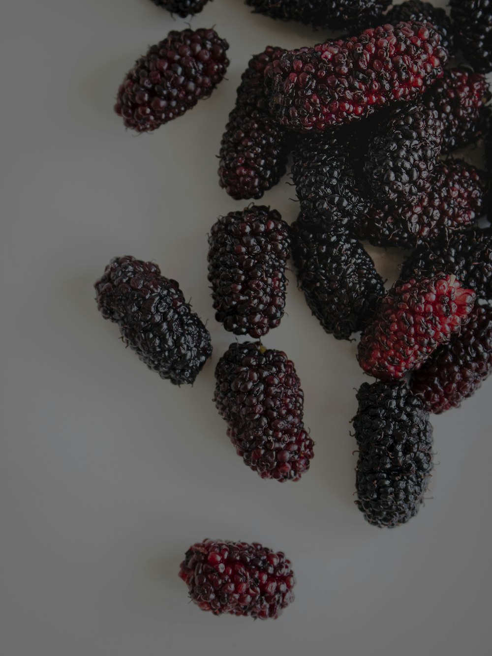 a pile of blackberries on a white surface