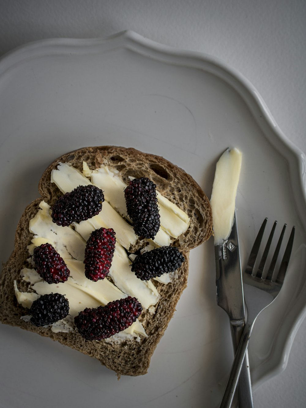 a white plate topped with a piece of bread covered in cheese and berries