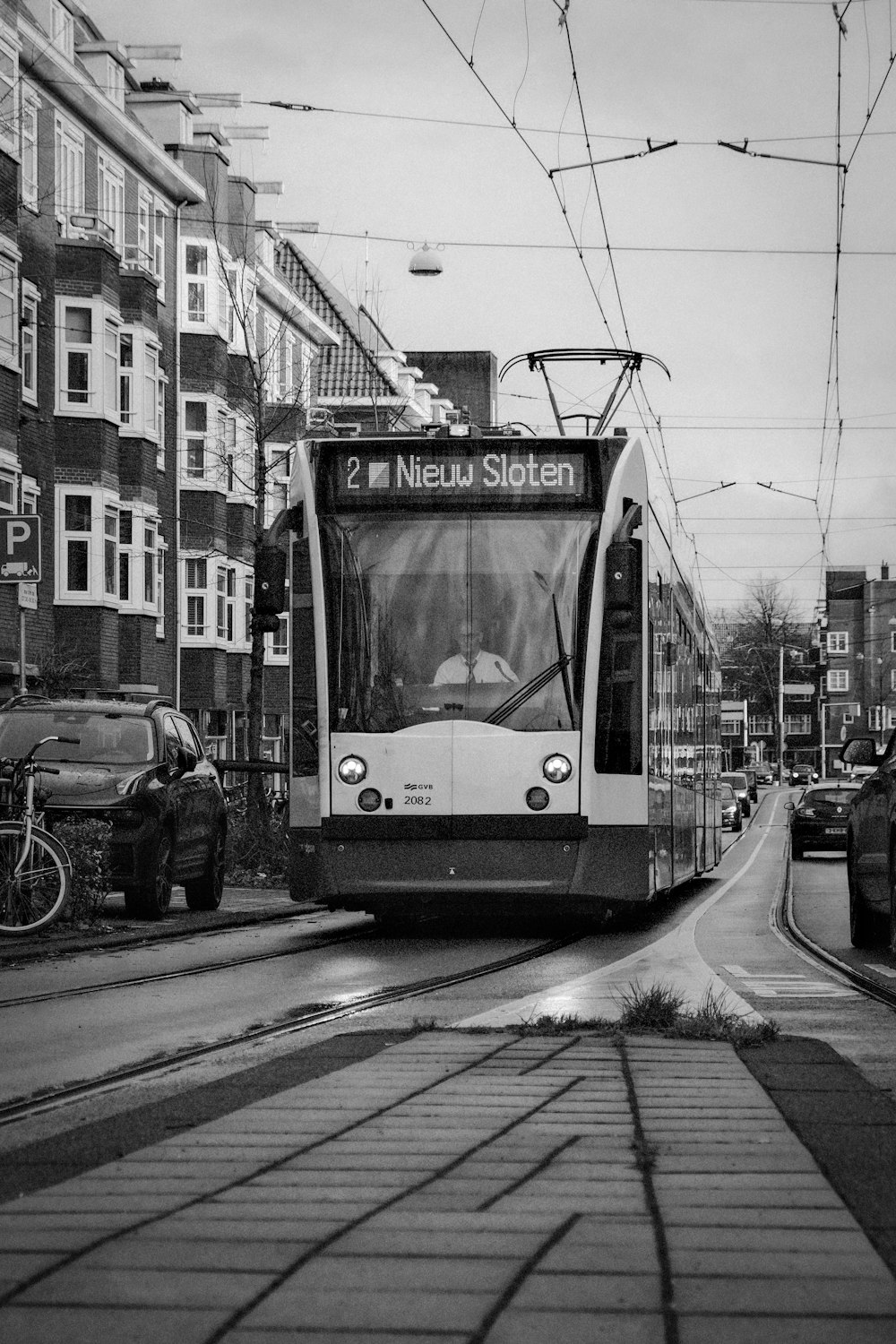 a black and white photo of a trolley on a city street