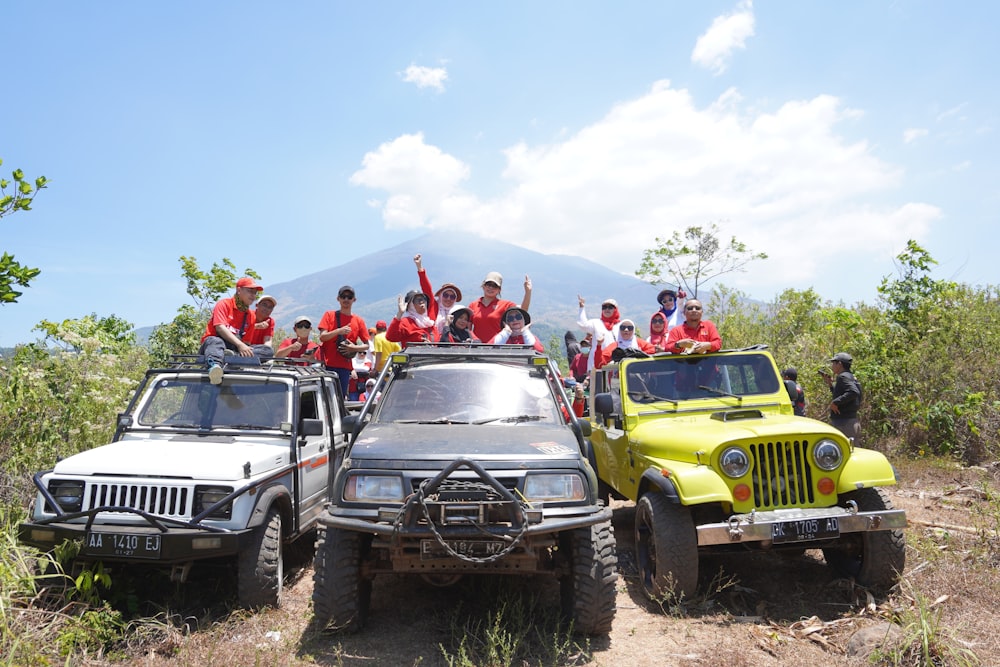 a group of people standing on top of four jeeps