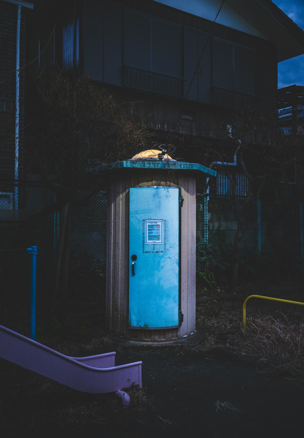 a blue outhouse sitting in the middle of a yard