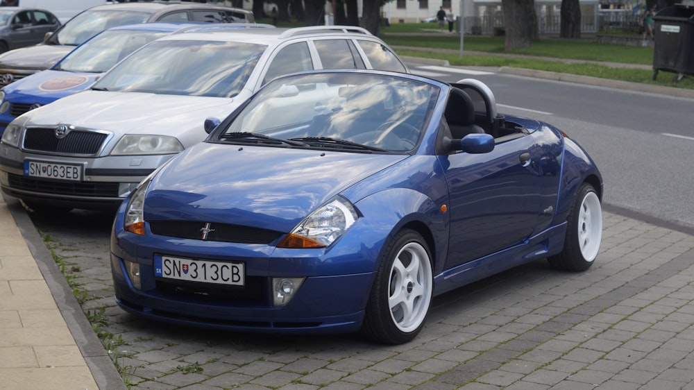 ein kleines blaues Auto, das neben einem Bordstein geparkt ist