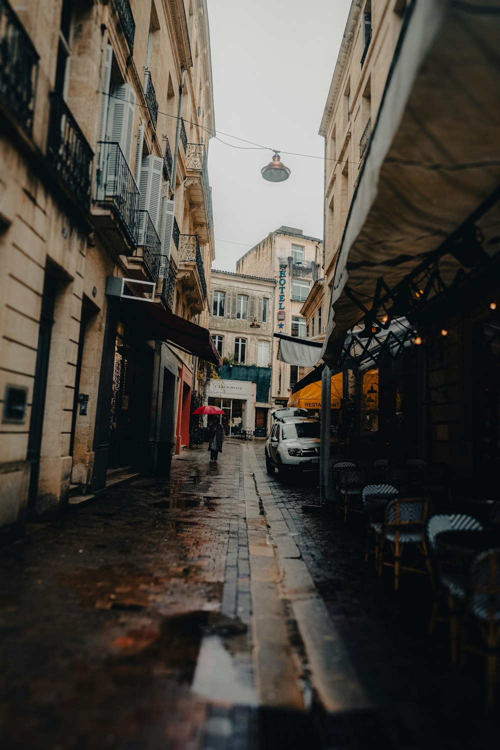 a narrow city street with tables and chairs