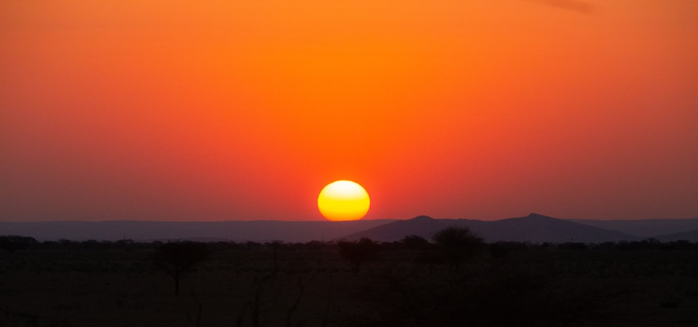 the sun is setting over the mountains in the distance