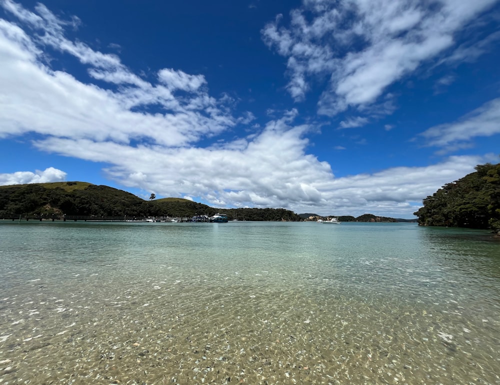 a body of water surrounded by trees and clouds