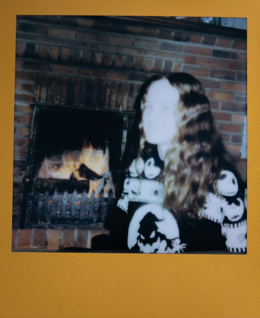 a woman with long hair standing in front of a fire place