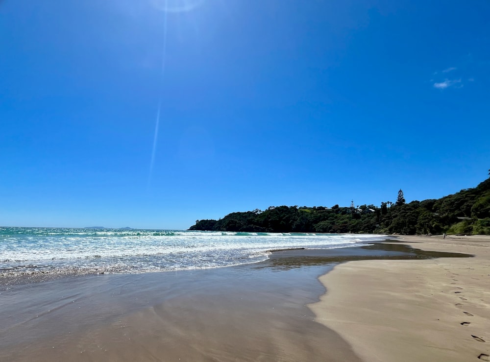 a sunny day at the beach with footprints in the sand