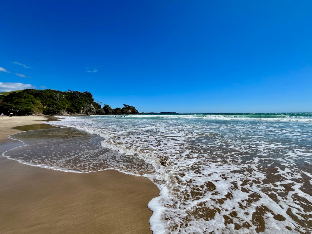 a sandy beach with waves coming in to shore