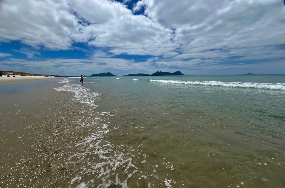 a person walking along a beach next to the ocean