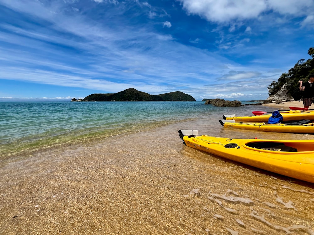 un groupe de kayaks jaunes assis au sommet d’une plage de sable