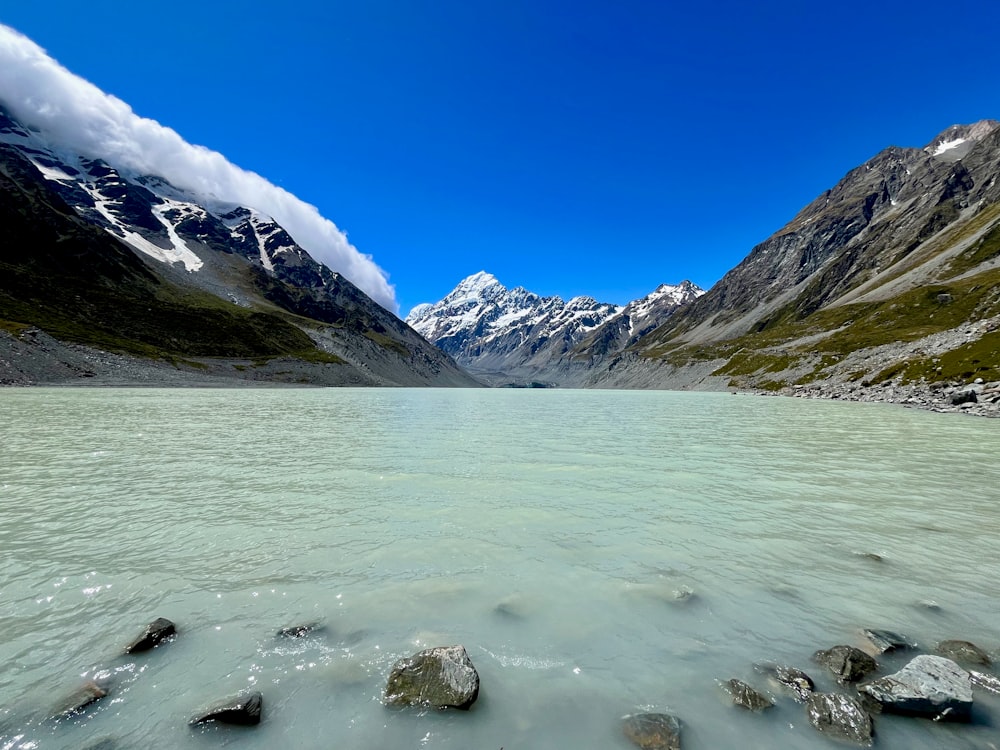 a body of water surrounded by mountains under a blue sky