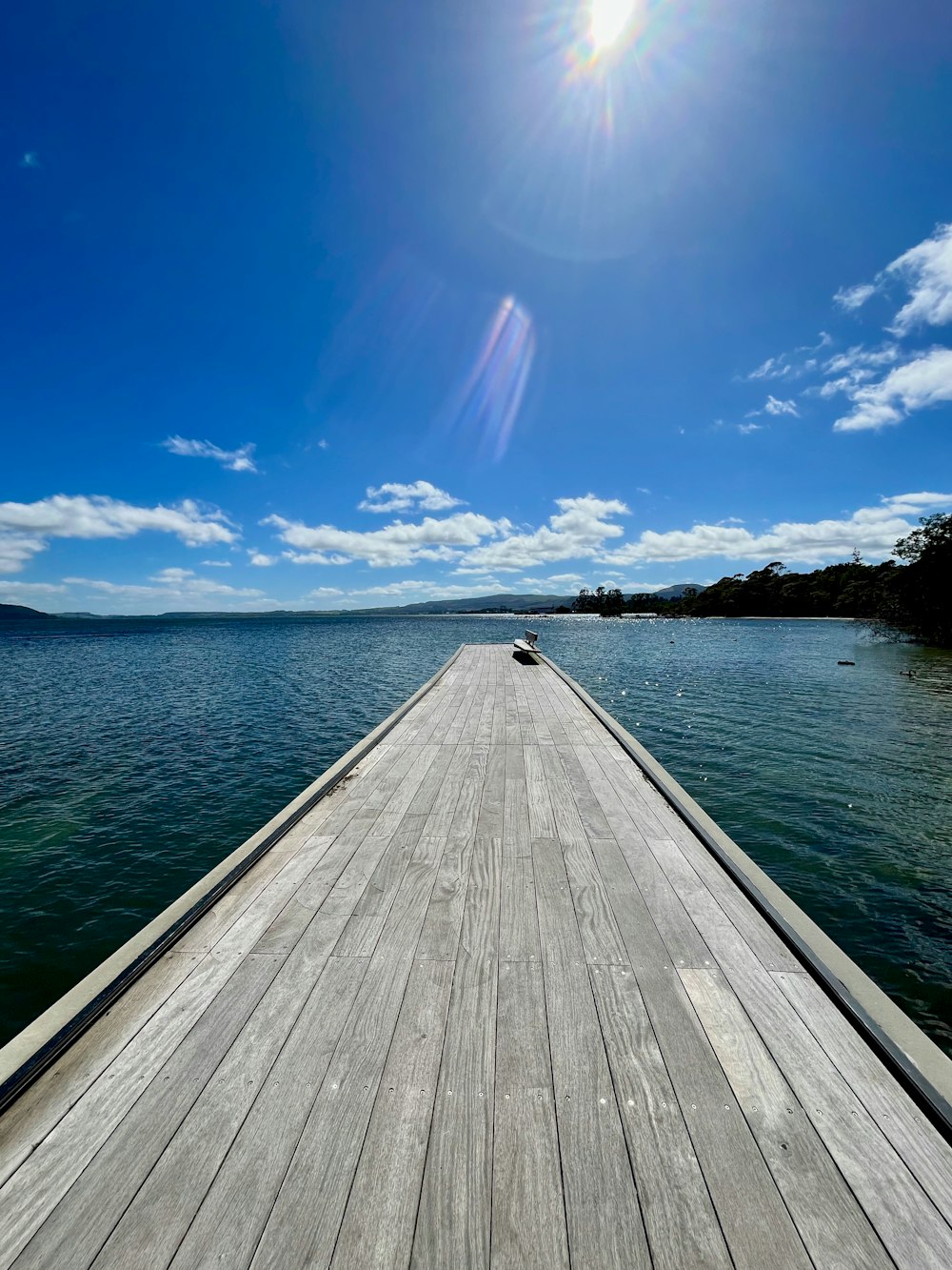 a wooden pier extending into the ocean under a blue sky
