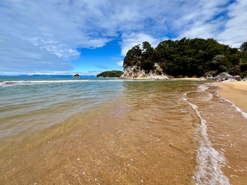 a sandy beach next to the ocean under a blue sky