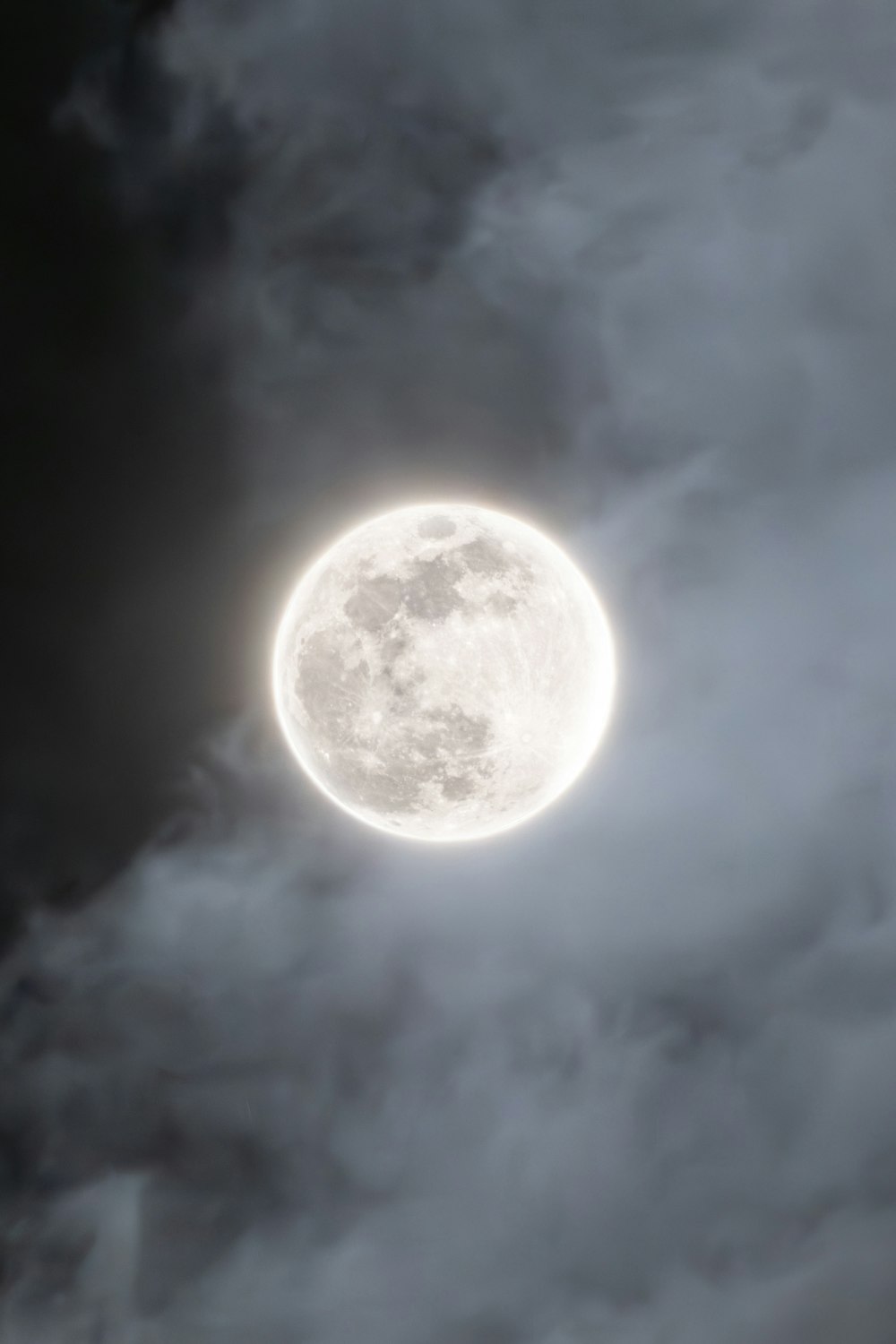 a full moon is seen through the clouds