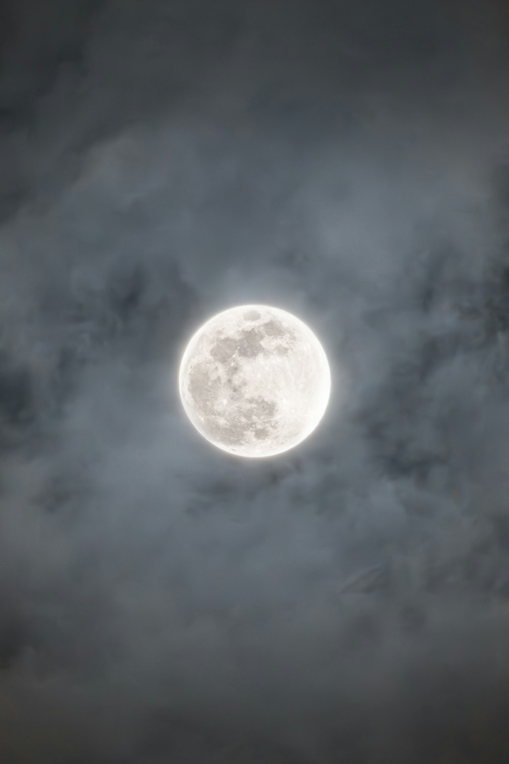 a full moon is seen through a cloudy sky