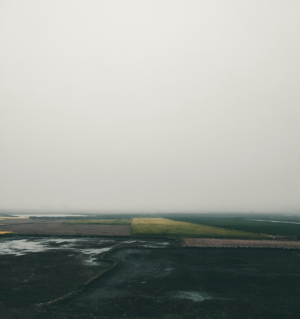 an airplane is flying over a field in the fog