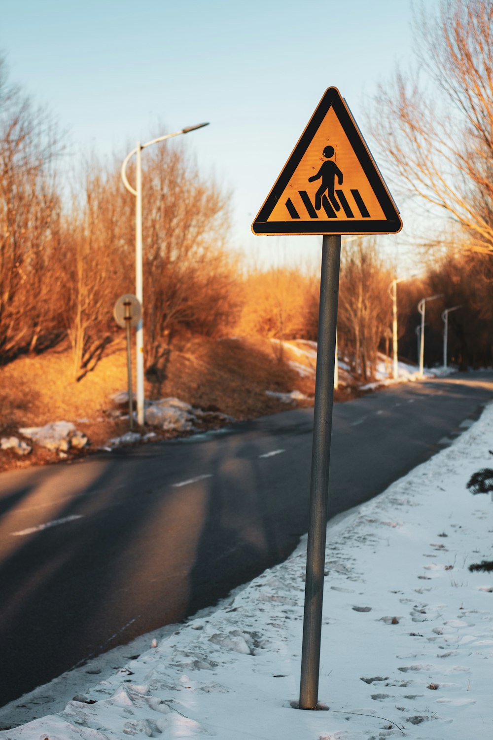 a yellow pedestrian crossing sign sitting on the side of a road