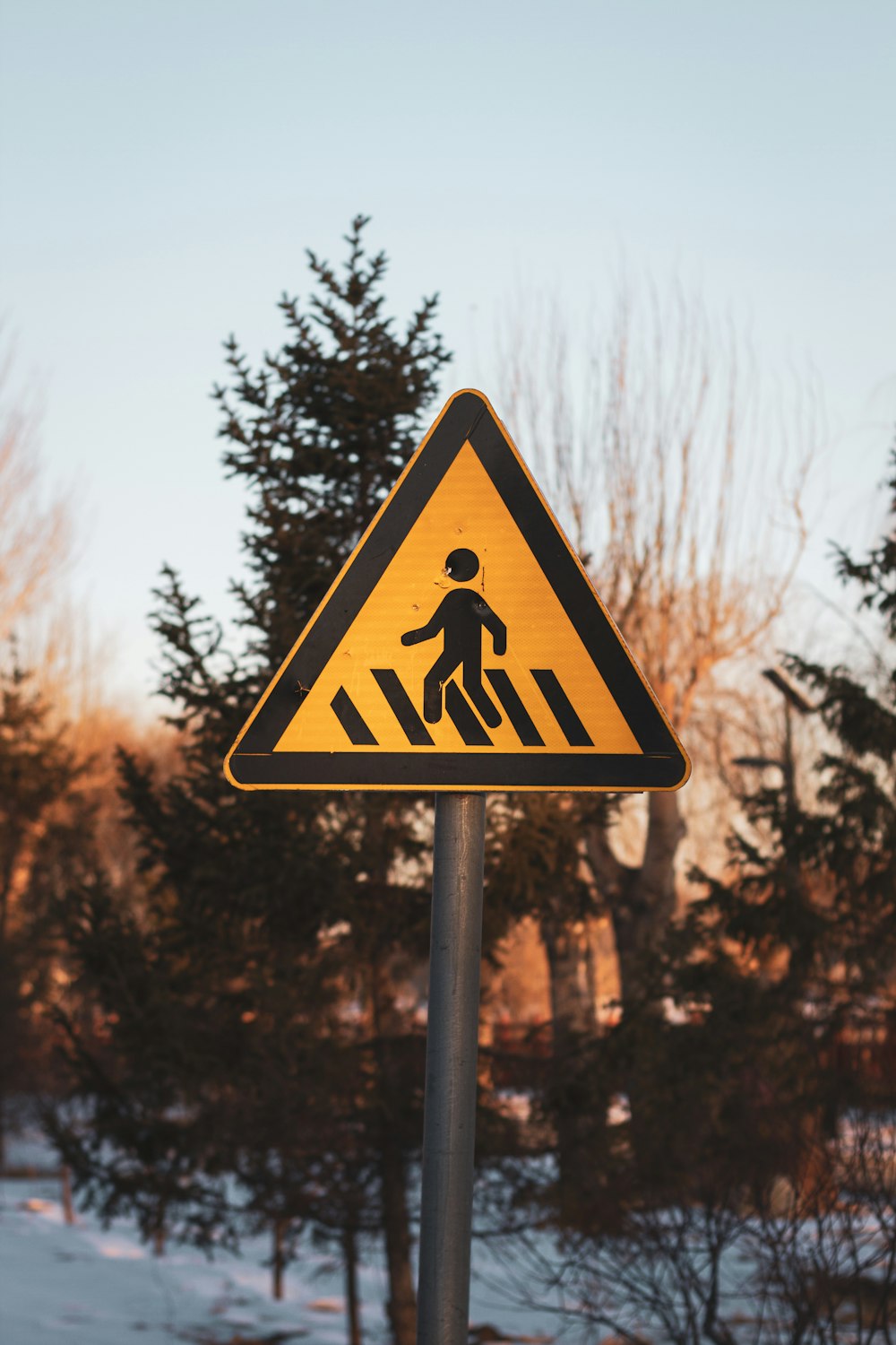 a yellow pedestrian crossing sign sitting on top of a metal pole