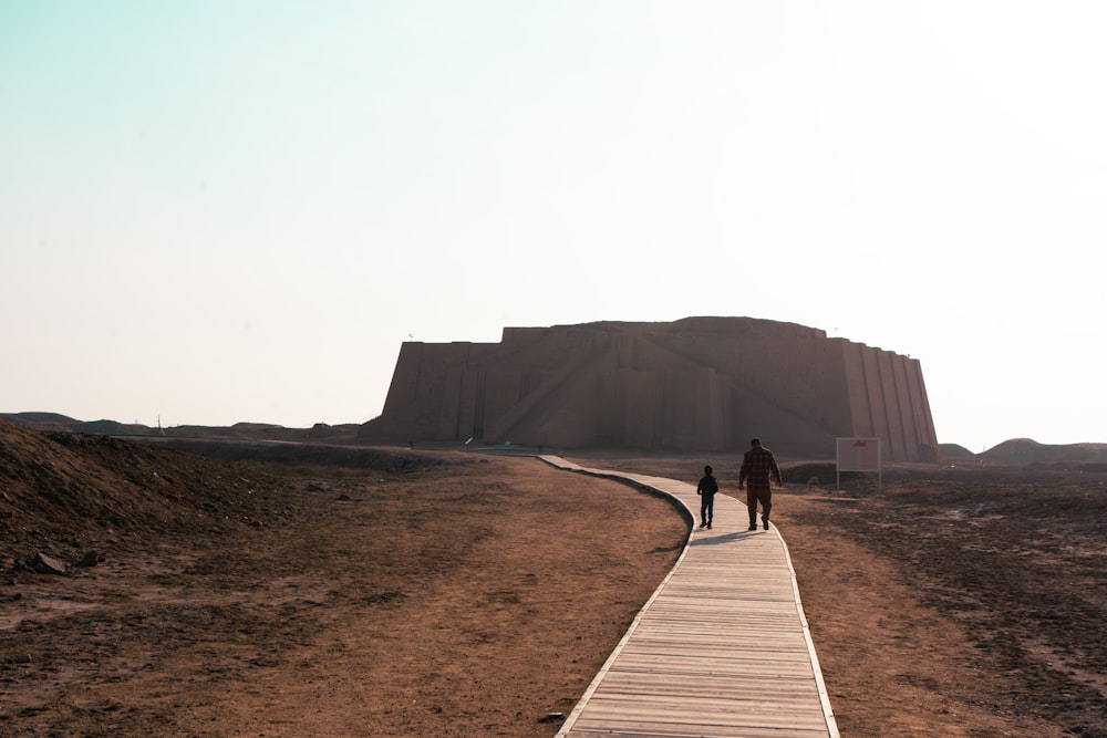 two people walking down a path in the desert
