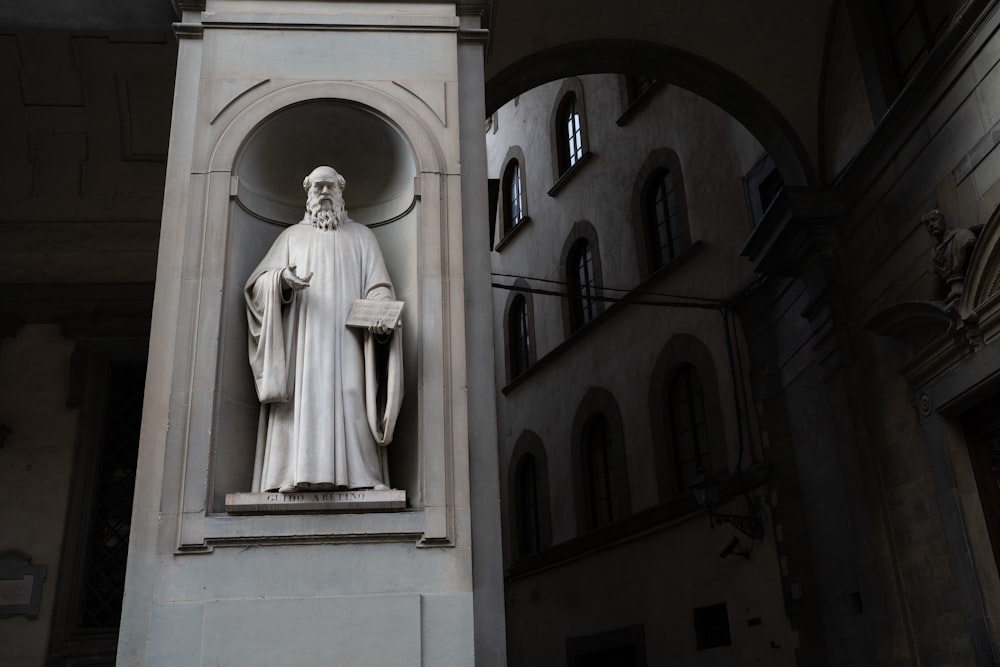 a statue of a man holding a book in front of a building