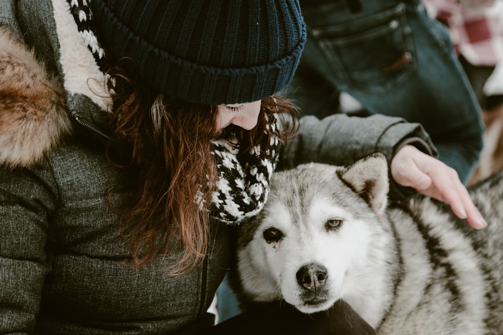 a woman is petting a husky dog