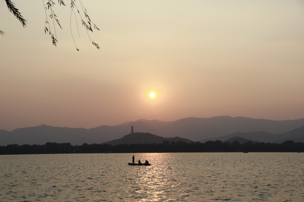 a person in a small boat on a lake at sunset