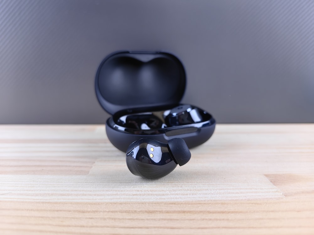 a pair of black ear buds sitting on top of a wooden table