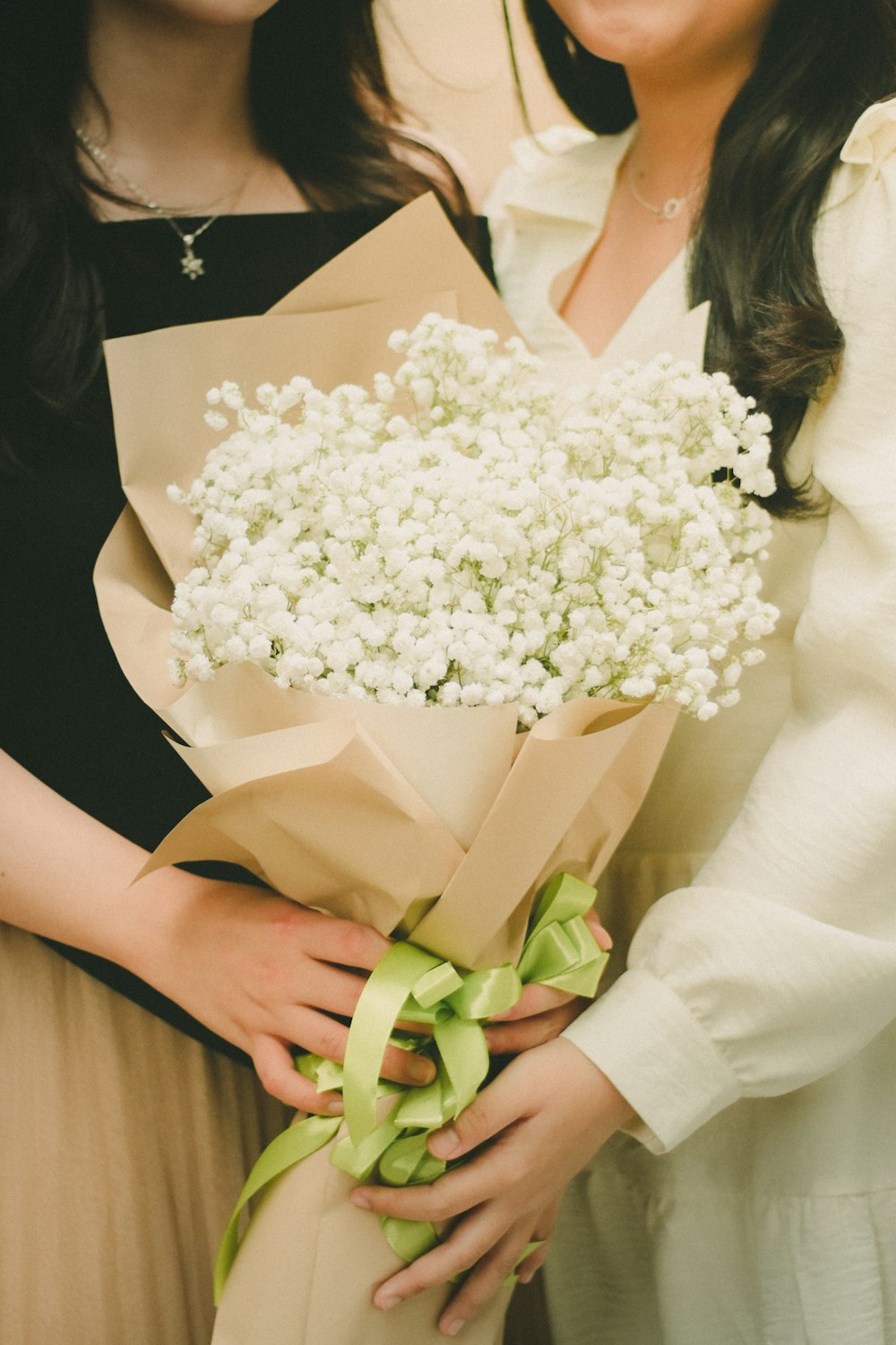 a couple of women standing next to each other holding a bouquet of flowers