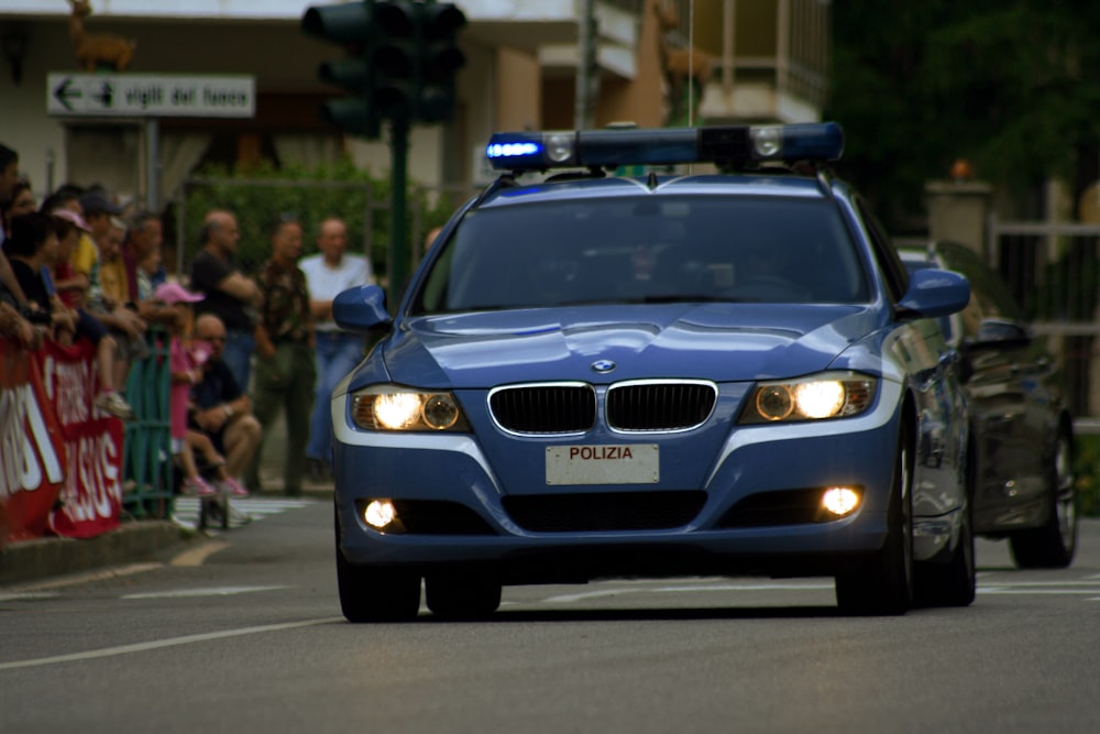 a police car driving down a street next to a crowd