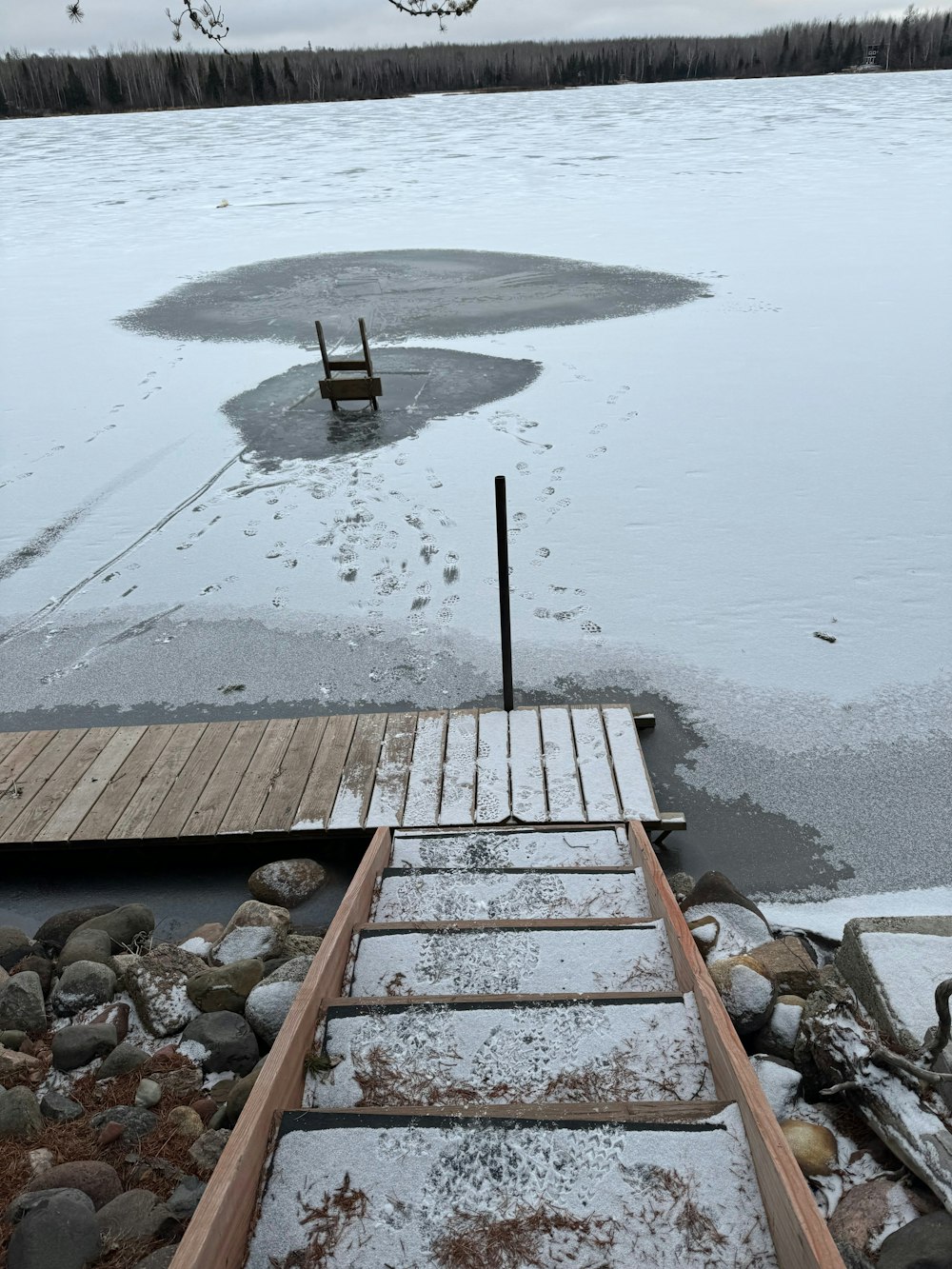 a wooden dock sitting on top of a frozen lake