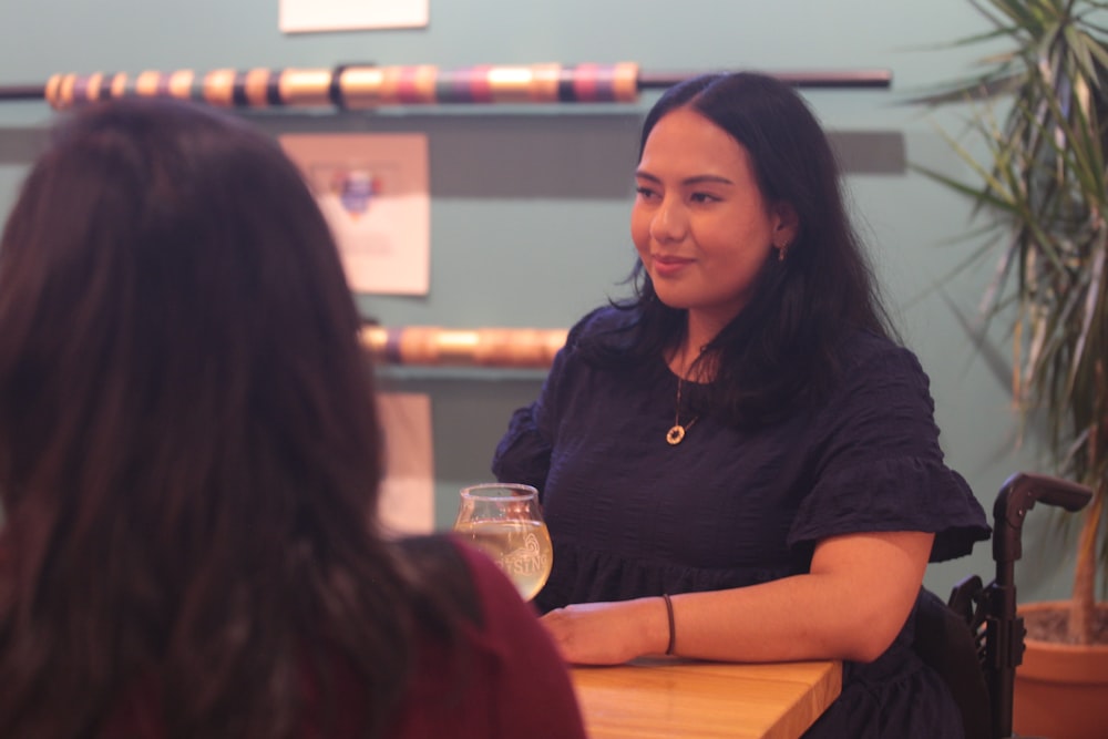 a woman sitting at a table with a glass of wine